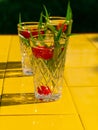 Refreshing summer drinks in crystal glasses green leaves raspberry on yellow tile background Sweet cold natural cocktail Royalty Free Stock Photo