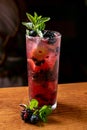 Summer mojito drink with blackberry, mint, lime, and ice on a bar counter