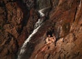 Refreshing summer. Two girls talking next to a waterfall. Sun light at sunset time. Sitting on rock wall. Editing space. Royalty Free Stock Photo