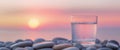 Refreshing Tranquility A Glass of Water on Polished Pebbles with a Sunset Background Royalty Free Stock Photo