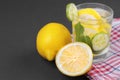 Water with lemon and cucumber and mint in a glass cup next to half a fresh lemon and cucumber slices on a black background Royalty Free Stock Photo