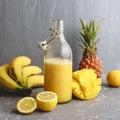 Refreshing yellow smoothie with lemons, banana, mango and pineapple on gray background Royalty Free Stock Photo