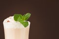 Refreshment coffee drink with fresh green mint, whipped cream, chocolate powder closeup, details, top sections of glass on brown.