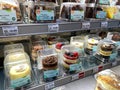 The refridgerated cake case of a Whole Foods Market grocery store with a variety of cakes for sale