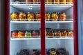 A refrigerated display case with cans of canned home products, a refrigerator with canned fruits and vegetables