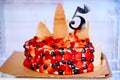 In refrigerator a birthday cake decorated with berries and a number five