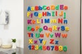 Refrigerator door with colorful magnetic letters and numbers in kitchen Royalty Free Stock Photo