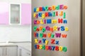 Refrigerator door with colorful magnetic letters and numbers in kitchen Royalty Free Stock Photo