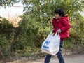 Refugee child carrying a bad of humanitarian aid with the logo of the UNHCR, the United Nations Agency for refugees