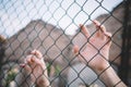 Refugee hands keeping metal fence mesh Royalty Free Stock Photo