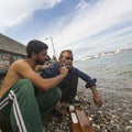 Refugee shaves the other on the beach. Many refugees come from Turkey in an inflatable boats. Royalty Free Stock Photo