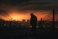 Refugees concept. Silhouette of refugee men near the border fence in the background of the urban landscape Royalty Free Stock Photo