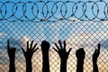 Refugees hands silhouette near the fence of barbed wire. Royalty Free Stock Photo