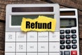 REFUND word on a small yellow sheet of paper placed on the calculator