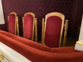 regal ornate rounded wood armed formal empty red velvet opera or movie or theatre chairs in curved row