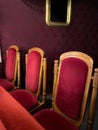 regal ornate rounded wood armed formal empty red velvet opera or movie or theatre chairs in curved row