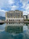 Regent Hotel is reflected in the water against the sky. Porto, Montenegro
