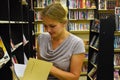 Woman chooses book in bookstore. Regiments with books in big library Royalty Free Stock Photo