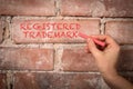 Registered Trademark. Text written with purple chalk on a red brick background
