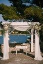Registration desk stands under a wedding awning decorated with flowers on the seaside
