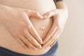 Regnant Woman holding her hands in a heart shape on her baby