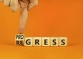 Regress or progress symbol. Businessman turns wooden cubes and changes the word Regress to Progress. Beautiful orange table orange