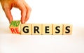 Regress or progress symbol. Businessman turns wooden cubes and changes the word Regress to Progress. Beautiful white table white