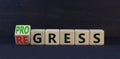 Regress or progress symbol. Turned wooden cubes and changed the word Regress to Progress. Beautiful black table black background.