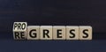 Regress or progress symbol. Turned wooden cubes and changed the word Regress to Progress. Beautiful black table black background.