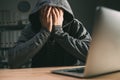 Regretful computer hacker covering face with hands in front of laptop Royalty Free Stock Photo