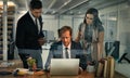 Regrouping as a team to catch up on their project. a team of colleagues using a laptop together on a night shift at work Royalty Free Stock Photo