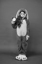 Regular day beginning. Adorable bunny hold alarm clock. Small girl in bunny costume. Child rabbit kigurumi. Girl bunny