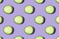 Regular seamless creative pattern of cucumber slices on a violet background.
