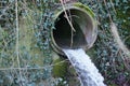 Regulated stream or brook coming from underground out of a large pipe in a small waterfall