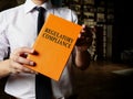 Regulatory compliance book in the hands of man with a tie.