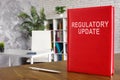 Regulatory update book on the wooden surface.