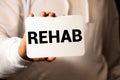 REHAB word on the card shown by a man Royalty Free Stock Photo