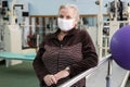 Rehabilitation after coronavirus infection. Elderly woman in face medical mask in a gym during covid-19 pandemic