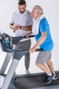 rehabilitation therapist checking time while assisting senior man exercising on treadmill Royalty Free Stock Photo