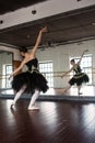 Rehearsal ballerina in the hall. White walls, dark wooden floor, dark ceiling, beautiful chandeliers,. The reflection of the