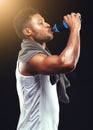 Rehydrating after an epic workout. Studio shot of a fit young man isolated on black.