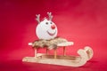 A reindeer bauble sitting on a sleigh, on the red background Royalty Free Stock Photo