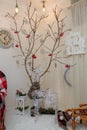 Reindeer garland, dry tree with red berries, snowflakes, clock. Happy New Year inscription on wall. Living room corner decorated Royalty Free Stock Photo