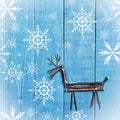 Reindeer made from dry sticks on wooden, blue background. Snow flaks image, ornament, craft