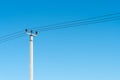 reinforced concrete pillar with high-voltage wires against a clear blue sky Royalty Free Stock Photo