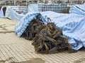 Reinforcing bars placed on the ground in the construction site, covered with rainproof cloths.