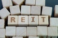 Reit, real estate investment fund concept, cube wooden block with alphabet building the word REIT on blackboard