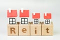 Reit, Real estate investment trust concept, miniature houses on cube wooden block with alphabet combine the word Reit on white