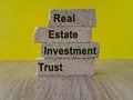 REIT real estate investment trust symbol. Concept words REIT real estate investment trust on brick blocks on beautiful yellow