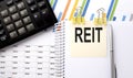 REIT text, written on a sticker with calculator,pen on the chart background Royalty Free Stock Photo